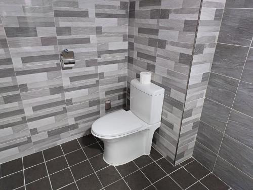a bathroom with a toilet in a tiled wall at Tongyeong Bridge Hotel in Tongyeong