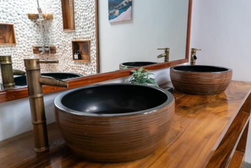 a bathroom with three sinks and two large wooden bowls at U Story Resort in Siquijor