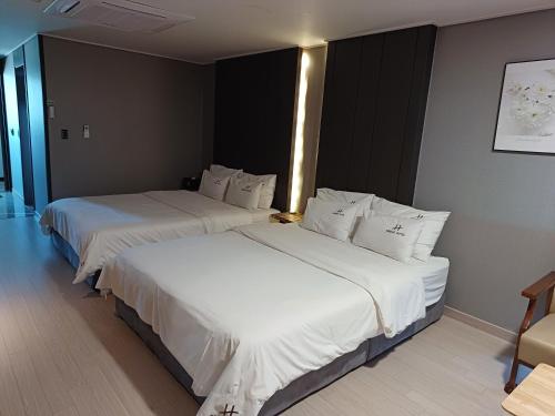 two beds in a hotel room with white sheets at Tongyeong Bridge Hotel in Tongyeong