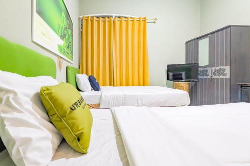 a hotel room with two beds and a tv at Urbanview Alza by RedDoorz in Tjiandjur