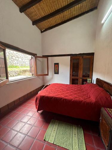 a bedroom with a red bed and two windows at La Ramada in Tafí del Valle