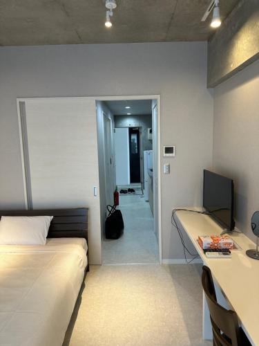 a bedroom with a bed and a desk with a computer at COZYSTAY group ブラウンシュガー in Miyako Island