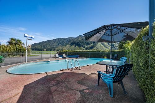 a swimming pool with a table and an umbrella at Linkwater Apartments - Two Bedroom Apartment in Linkwater