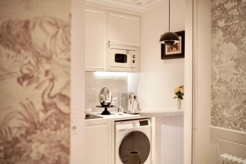 une petite cuisine avec des placards blancs et un lave-linge dans l'établissement Splendid Artist Apartment 2P, à Paris