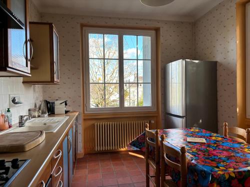une cuisine avec une table et un réfrigérateur dans l'établissement Havre de paix cosy avec jardin proche du centre-ville de Poitiers, à Poitiers