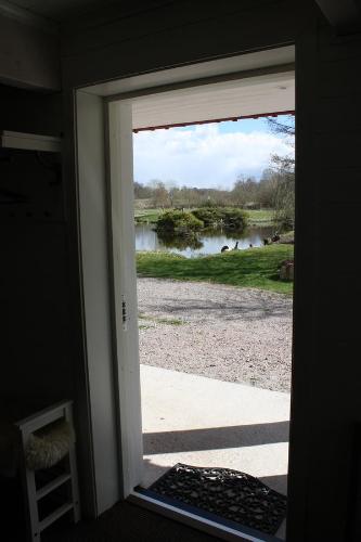 a door open to a view of a lake from a house at Nolgårdens Turistboende in Ugglum