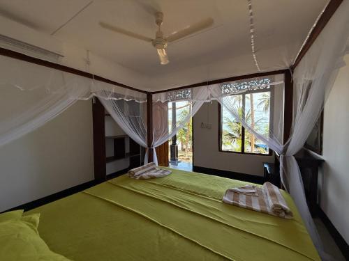 a green bed in a room with a window at Kudah Bay Surf Camp in Arugam Bay