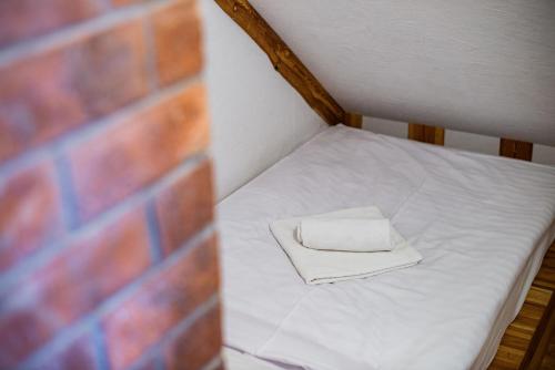 a small bed with a white towel on it next to a brick wall at Turistična kmetija Grabnar in Bled