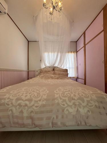 a bedroom with a large bed with a chandelier at condominium [Signal Resort] in Kujukuri