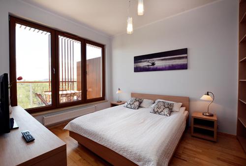 a bedroom with a bed and a large window at Royal Olympic Park in Kołobrzeg
