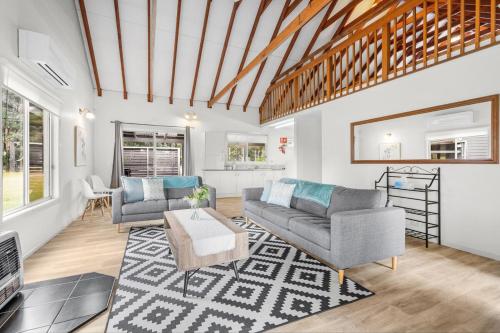 a living room with two couches and a rug at Madigan Cottages - Australiana in Lovedale