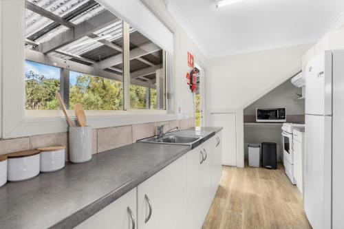 a kitchen with white cabinets and a sink and a window at Madigan Cottages - Australiana in Lovedale