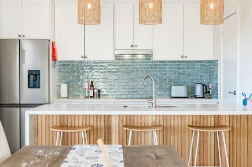 a kitchen with a sink and a counter with stools at Dinga Coastal Hamptons style in Aldinga Beach