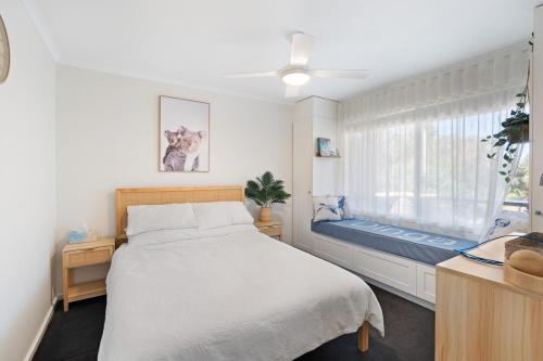 a bedroom with a bed and a window with a bench at Dinga Coastal Hamptons style in Aldinga Beach