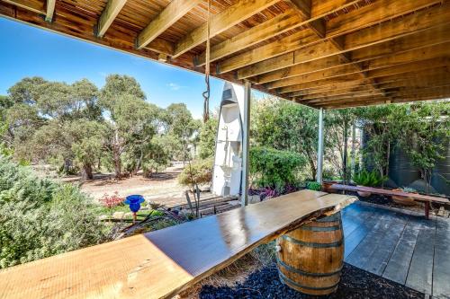 a large wooden bench on a patio with trees at Dinga Coastal Hamptons style in Aldinga Beach