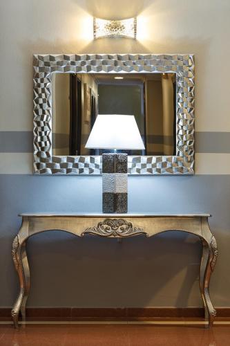a mirror on a wall above a bench with a lamp at Hotel Doña Luisa in San Luis de Sabinillas