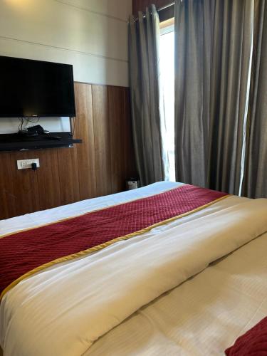 a bedroom with a bed with a television and a window at Radhika Residency At Omaxe Eternity in Vrindāvan