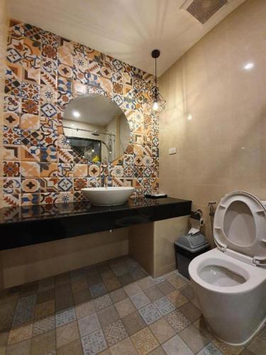 a bathroom with a toilet and a sink and a mirror at THE S VILLAS HOTEL in Nakhon Phanom