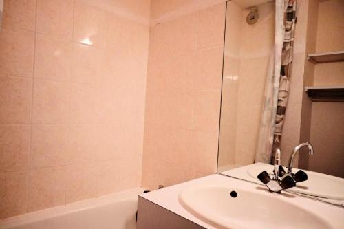 La salle de bains est pourvue d'un lavabo et d'une baignoire avec un miroir. dans l'établissement Résidence Michailles - En centre station et proche des pistes MAE-1794, à Peisey-Nancroix