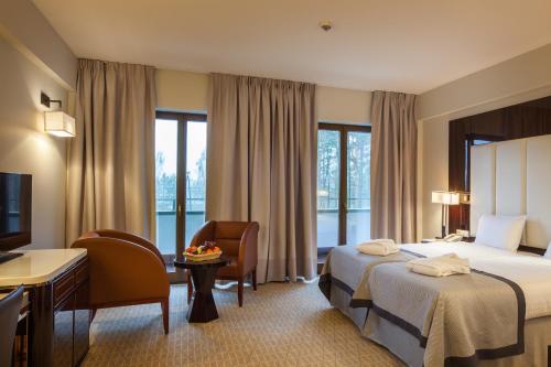a hotel room with a bed and a desk and a tv at Natura Mazur Resort & Conference in Warchały