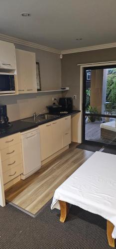 a kitchen with white cabinets and a bed in a room at C'est La Vie in Tauranga