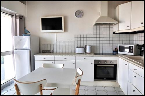 une cuisine blanche avec une table et des chaises blanches dans l'établissement Le plongeoir, à Saint-Trojan-les-Bains