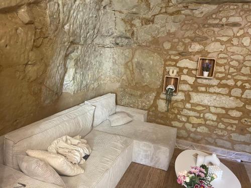 sala de estar con sofá en una pared de piedra en La Cachette Futuroscope, en Beaumont