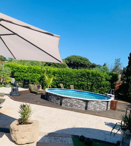- une piscine avec un parasol dans la cour dans l'établissement Villa NYVIONI, proche de la mer, avec piscine et SPA, au Grau-dʼAgde