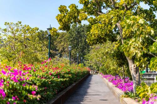 a walkway through a garden with pink flowers at TUI BLUE Maduzi Hotel Bangkok in Bangkok