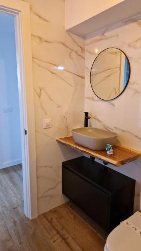 Un baño con un lavabo y un espejo sobre un mostrador. en Apartamentos Playa de Camariñas, en Camariñas