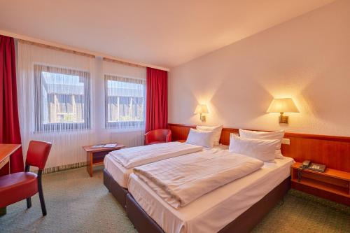 a hotel room with a large bed and red curtains at Mercure Hotel Bad Duerkheim An Den Salinen in Bad Dürkheim