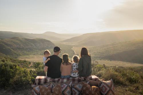 a family sitting on a rock looking at the valley at Gondwana Game Reserve in Kleinberg