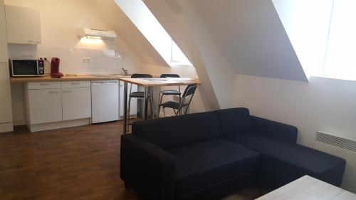 a living room with a couch and a kitchen at Au Pigeon Blanc in Andouillé