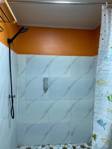 a shower in a bathroom with white tiles at Three Ken Homestay & Cafe in Manado