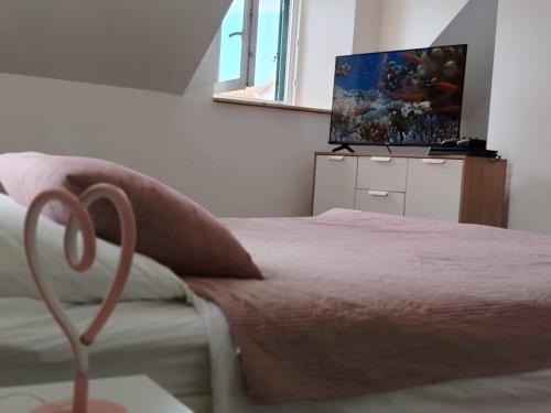 a bedroom with a bed and a flat screen tv at Ema in Prvić Šepurine