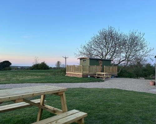 a picnic table and a house in a field at Fernlea Luxury Shepherds Hut & Hot Tub in Boosbeck