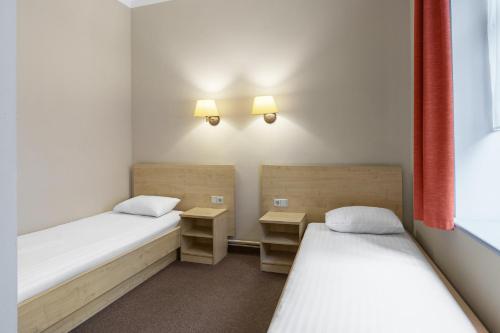 a small room with two beds and two tables at Rija Domus Hotel in Rīga