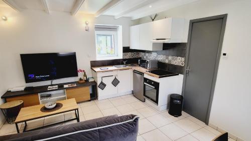 Il comprend un salon avec une cuisine et une télévision. dans l'établissement KerElo Le Ptit St Roch, maisonnette cosy, mer 5km, Ploudalmezeau, à Ploudalmézeau