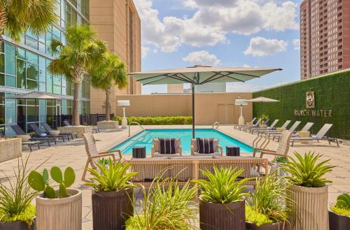 a pool with chairs and an umbrella in a courtyard at Hyatt Regency Houston Galleria in Houston