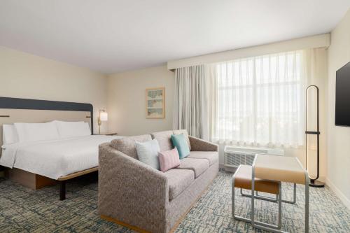 a hotel room with a bed and a couch at Homewood Suites By Hilton Thornton Denver in Thornton
