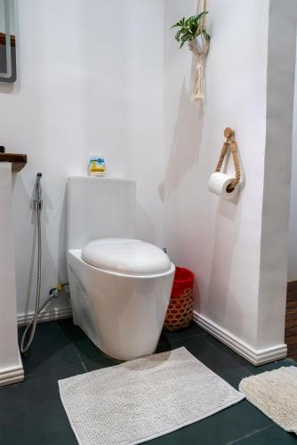 a white toilet in a bathroom with rugs at U Story Resort in Siquijor