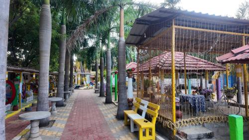 a park with tables and benches and palm trees at Le Royal Resort- By the Beach in Tarangambādi