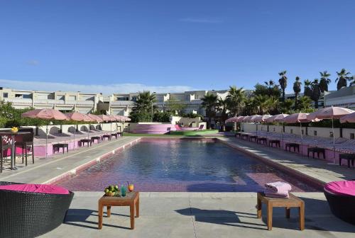une piscine avec chaises et parasols dans un complexe hôtelier dans l'établissement LOVE ROOM Jardin d'Eden JE108 - Suite Junior Premium, au Cap d'Agde