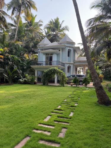 a house with a palm tree in front of it at Sea Breeze, Guhagar in Guhagar
