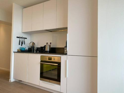 Il comprend une cuisine blanche équipée d'une cuisinière et d'un réfrigérateur. dans l'établissement Appartement rénové avec jardin, WIFI, parking à 750m de la plage à Perros-Guirec - FR-1-368-452, à Perros-Guirec