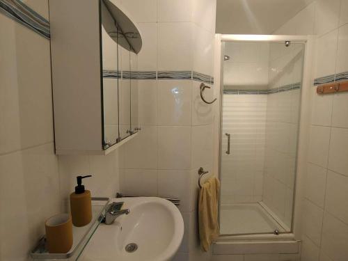 une salle de bain blanche avec un lavabo et une douche dans l'établissement Appartement T2 avec balcon vue port et accès piscine - FR-1-195-116, au Barcarès