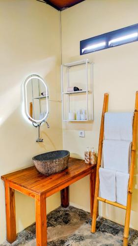a bathroom with a sink and a mirror on a table at Nila Chandra Bungalows in Ubud
