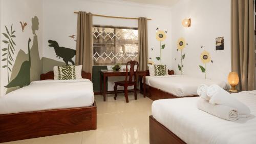 a room with three beds and a desk with a table at Babel Siem Reap Guesthouse in Siem Reap