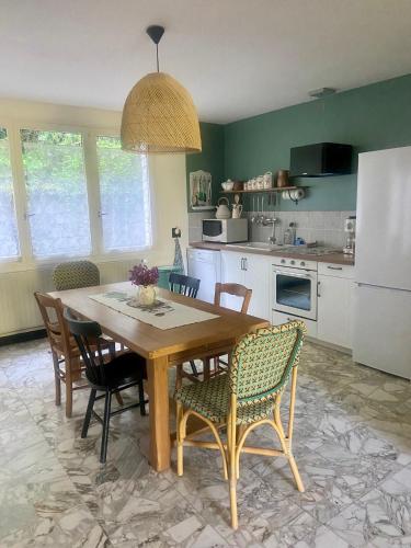 une cuisine avec une table en bois avec des chaises et un réfrigérateur dans l'établissement Le Moulin de Frise, à Frise