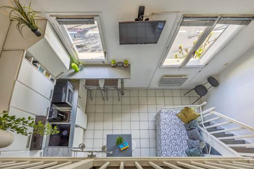 une cuisine mansardée avec deux fenêtres et un escalier dans l'établissement The Cocon de Biarritz, à Cambo-les-Bains